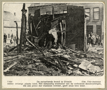 98729 Afbeelding van de resten van het door een brand verwoest complex houten noodwoningen op een terrein aan de ...